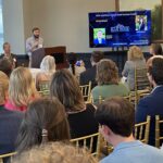 A member of the SCRA presentation team stands behind the podium to present the small business finalists of the Meet the Finalists event