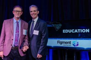 Jeff Borckardt with FIgment Learning Labs stands on stage with Dr. Dirk Brown of the University of South Carolina McNair Institute for Entrepreneurism and Free Enterprise to accept the Education Award at the 2025 InnoVision Awards