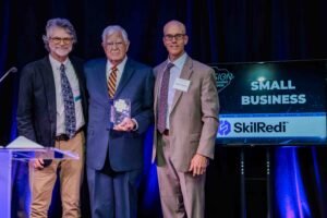 Richard Murphy and Dr. Robert Couch of SkilRedi stand on stage with Mat Hultquist of the Hultquist Firm as they accept the Small Business award at the 2025 InnoVision Awards