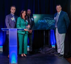 Corey Leydig, Ritubarna Banerjee and Malichi Flemming with Advent Innovaions stand on stage with Bill Charlton of Velux to accept the Sustainability award at the 2025 InnoVision Awards