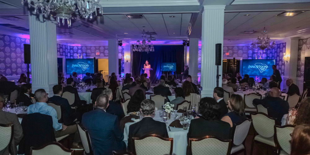 FOX Carolina journalist Myra Ruiz stands on stage behind a podium and speaks as the emcee of the 2025 InnoVision Awards